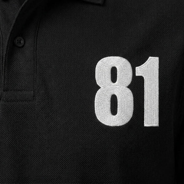 Gros plan sur le 81 brodé en blanc du polo noir Oscar Piastri