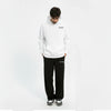 Homme regardant vers le sol portant un hoodie blanc et pantalon noir assorti avec logo “TOURISMO”
